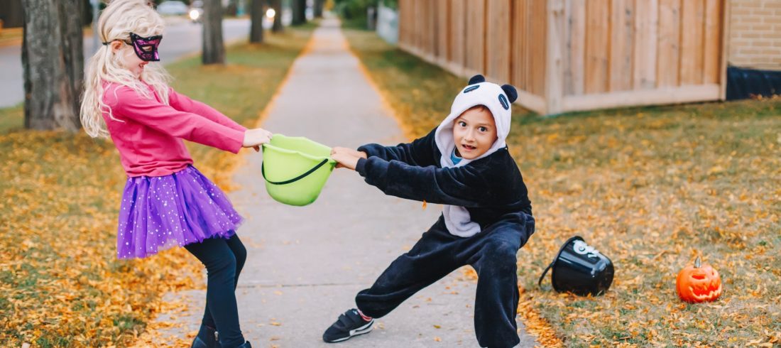 Friends children fighting for basket after Halloween celebration trick or treat. Siblings quarrel.