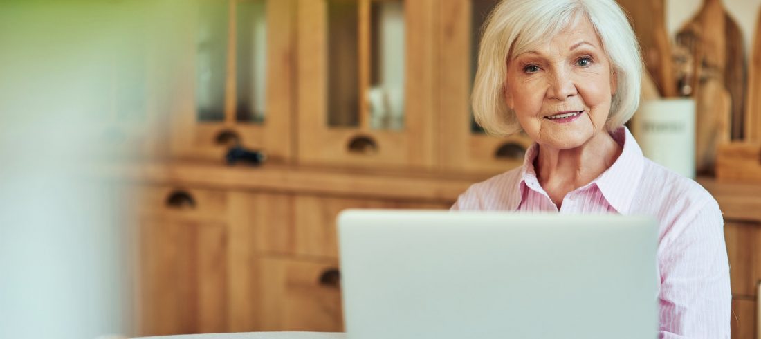 Happy elder female using computer at home