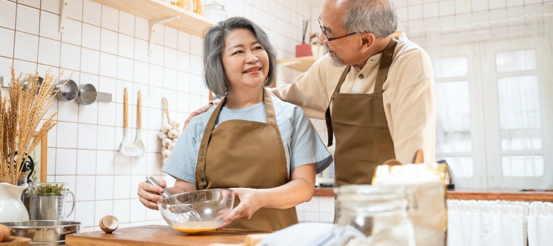 Asian Senior elderly couple standing in kitchen at house feeling happy and enjoy retirement life